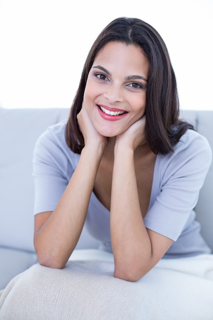 Souriante belle brune assise sur le canapé