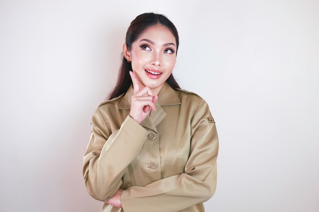 Souriante belle femme asiatique pointant le doigt vers le haut pour un espace vide en studio fond isolé blanc