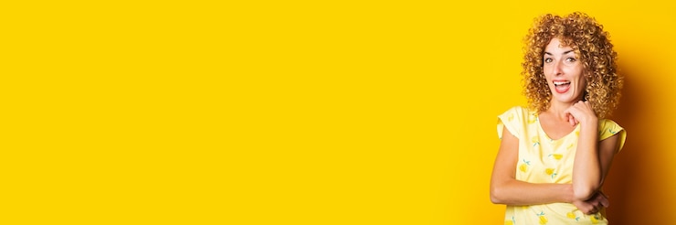 Photo souriante belle jeune femme aux cheveux bouclés sur un fond jaune vif