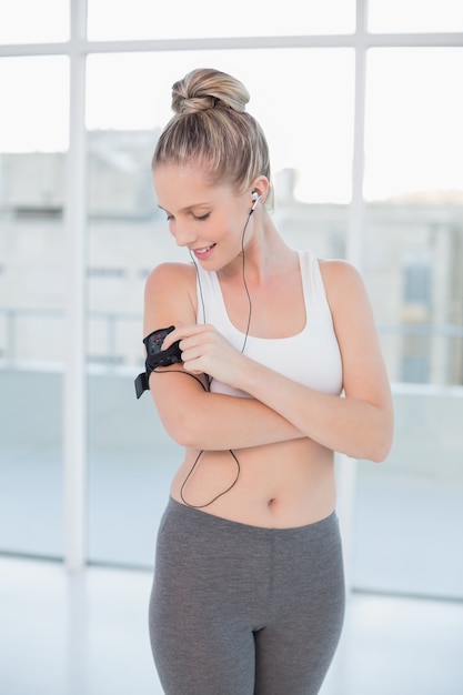 Souriante blonde sportive changeant de musique sur son lecteur mp3