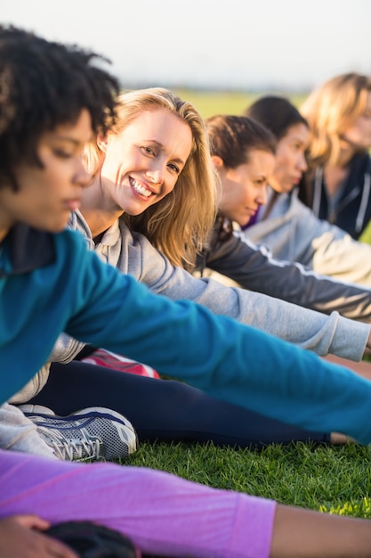 Souriante blonde sportive qui s&#39;étend pendant le cours de conditionnement physique