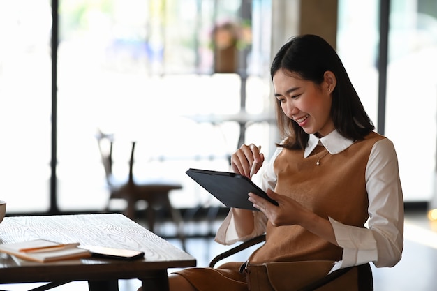 Souriante femme entrepreneur de petite entreprise travaillant sur tablette numérique.