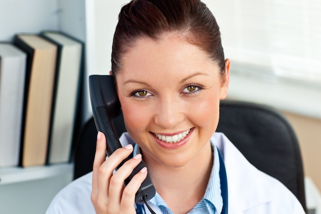 Souriante femme médecin téléphonant dans son bureau