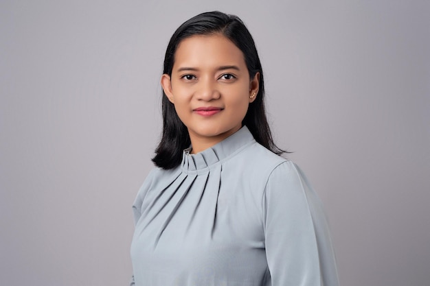 Photo souriante, heureuse, jeune femme d'affaires asiatique d'une trentaine d'années, confiante devant la caméra, isolée sur un fond gris.