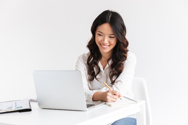 Souriante jeune femme d'affaires asiatique, prendre des notes