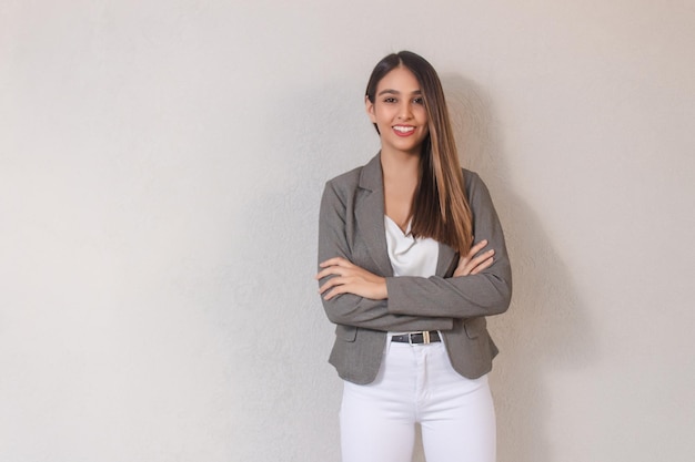 Souriante jeune femme d'affaires avec les bras croisés sur fond blanc