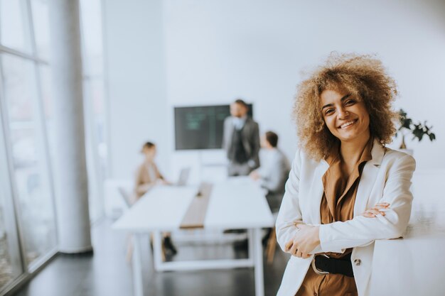 Souriante jeune femme d'affaires debout dans un bureau moderne