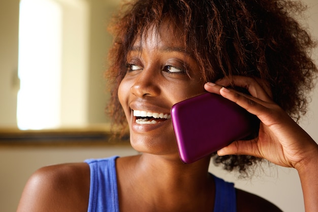 Souriante jeune femme africaine parlant sur téléphone portable