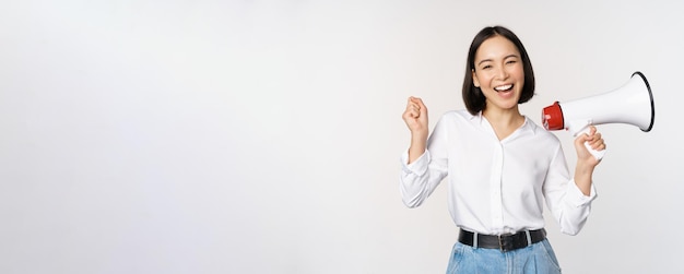 Souriante jeune femme asiatique posant avec le concept de mégaphone d'annonce de nouvelles et d'information standin