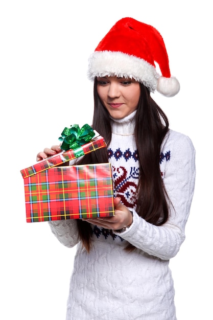 Souriante jeune femme au chapeau de noël rouge sur fond blanc avec des cadeaux