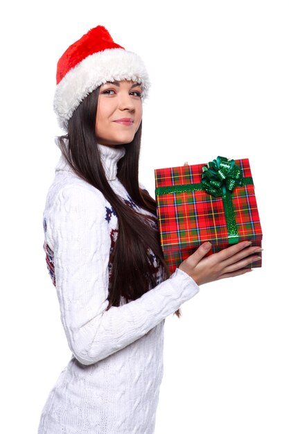 Souriante jeune femme au chapeau de noël rouge sur fond blanc avec des cadeaux