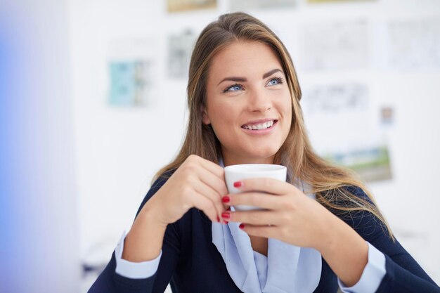 Souriante jeune femme ayant une pause-café au bureau