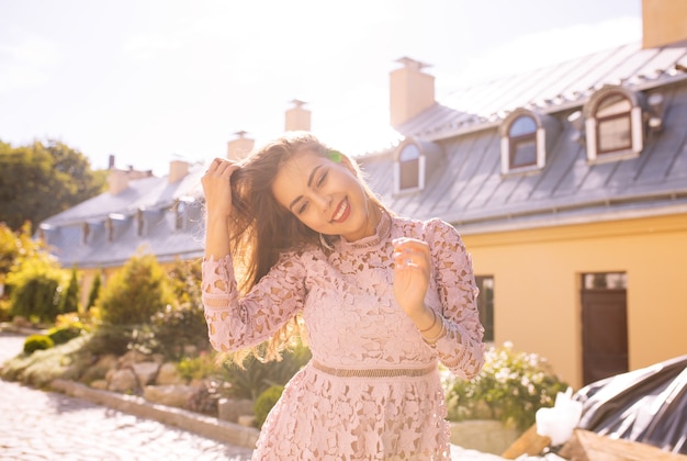 Souriante jeune femme brune posant dans la ville avec les reflets du soleil