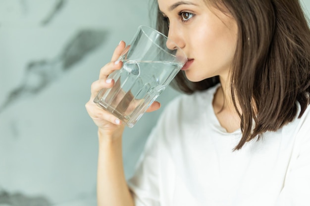 Souriante jeune femme buvant de l'eau dans la cuisine