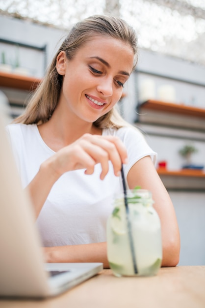 Souriante jeune femme buvant de la limonade.