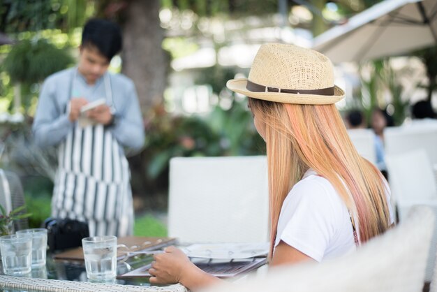 Souriante, jeune femme, dans, a, restaurant, à, les, menu, dans, mains, jeune femme, choisir, à partir, a, restaurant, menu