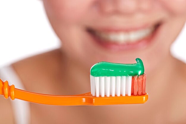 Souriante jeune femme avec des dents saines tenant une brosse à dents