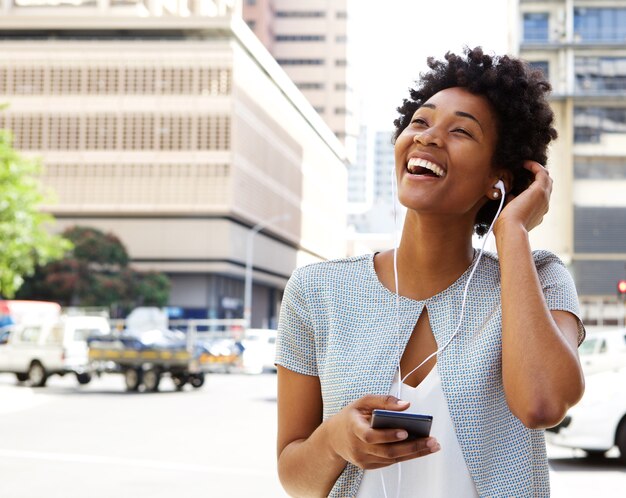 Souriante jeune femme écoute de la musique sur les écouteurs