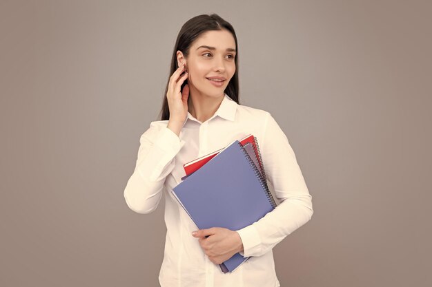 Souriante jeune femme étudiante tenant un livre sur fond gris isolé Modèle montrant émotionnellement les expressions faciales