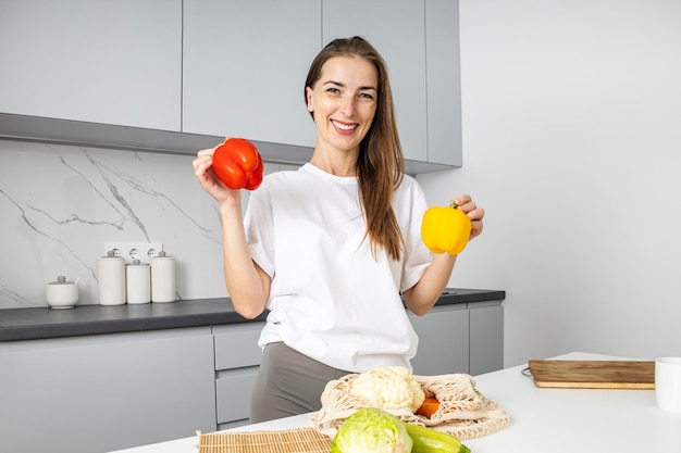 Souriante jeune femme exposant les achats du magasin dans la cuisine