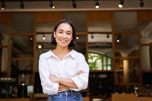 Souriante jeune femme gérante propriétaire de café croiser les bras sur la poitrine à la confiance debout devant r