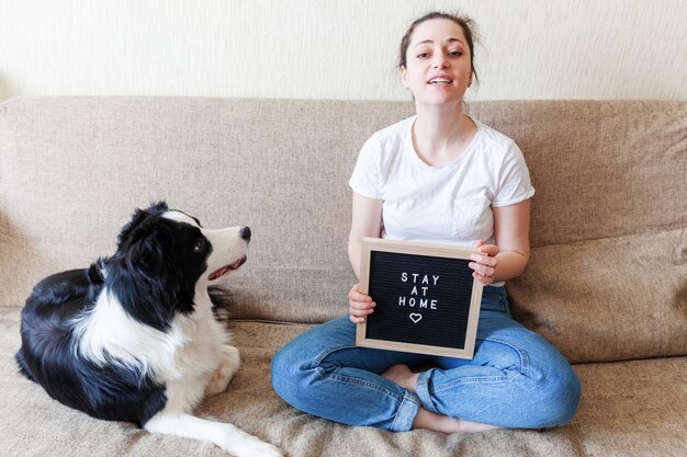 Souriante jeune femme jouant avec mignon border collie sur canapé à la maison à l'intérieur