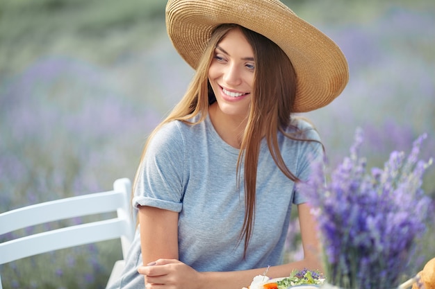 Souriante jeune femme magnifique posant dans un champ de lavande