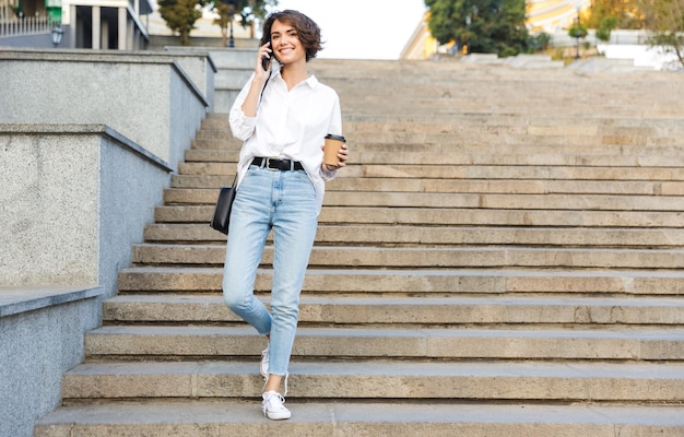 Souriante jeune femme marchant en bas dans la rue