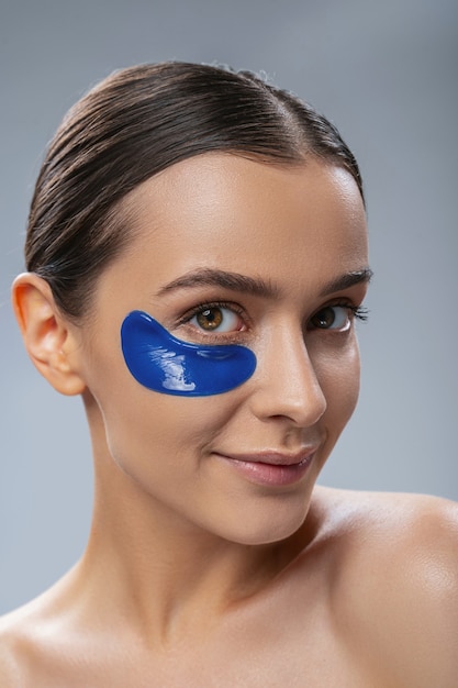 Souriante jeune femme avec masque anti-âge sous les yeux