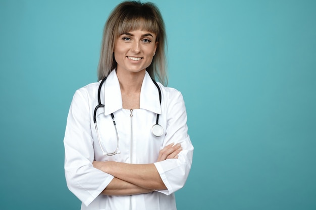 Souriante jeune femme médecin avec un stéthoscope debout sur un espace bleu