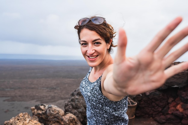 Souriante jeune femme mettant la main juste devant la caméra avec un geste drôle