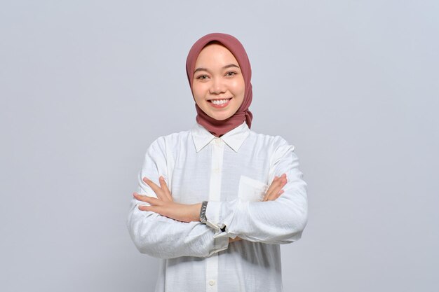 Souriante jeune femme musulmane asiatique debout avec les bras croisés et à la confiance isolé sur fond blanc