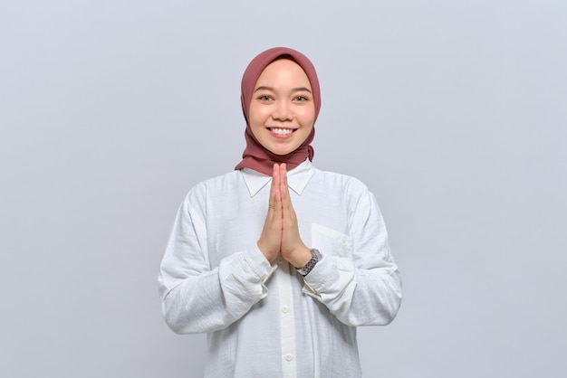 Souriante jeune femme musulmane asiatique gesticulant Eid Mubarak salutation isolé sur fond blanc