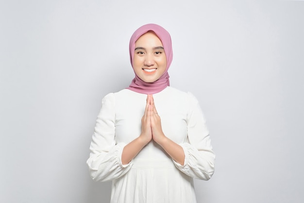 Souriante jeune femme musulmane asiatique gesticulant Eid Mubarak salutation isolé sur fond blanc