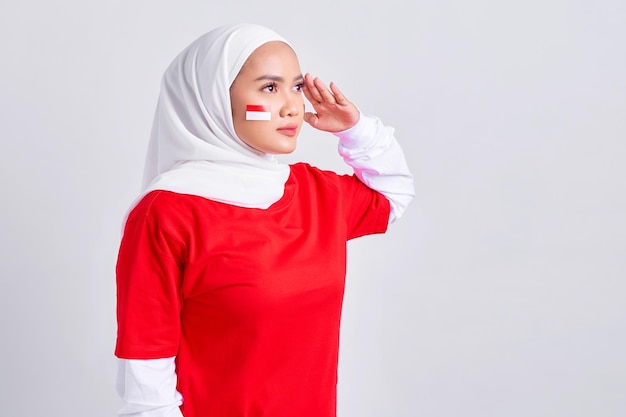 Souriante jeune femme musulmane asiatique en tshirt blanc rouge célébrant la fête de l'indépendance indonésienne le 17 août et montrant un geste de respect isolé sur fond blanc