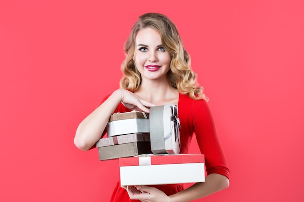 Souriante jeune femme en robe rouge avec des cadeaux