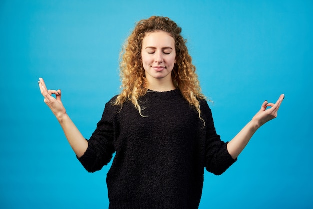 Souriante jeune femme rousse confiante attrayante et reposante avec méditer les mains