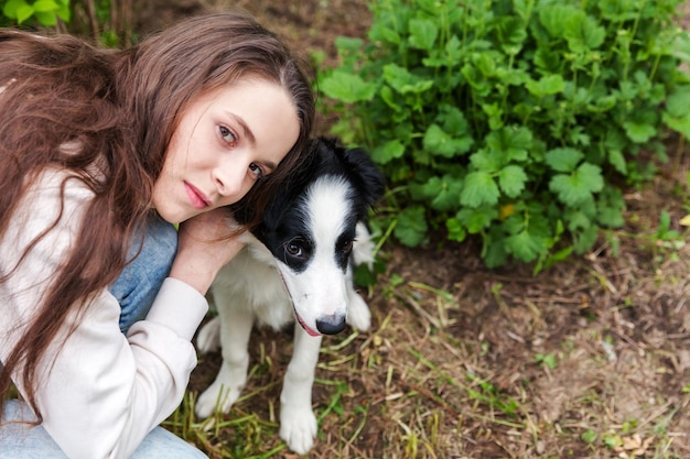 Souriante jeune femme séduisante embrassant huging mignon chiot border collie dans le fond extérieur du parc de la ville d'été