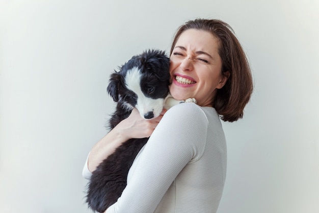 Souriante jeune femme séduisante embrassant mignon chiot chien border collie isolé sur blanc