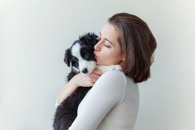 Souriante jeune femme séduisante embrassant mignon chiot chien border collie isolé sur fond blanc. Fille étreignant un nouveau membre adorable de la famille. Concept de soins pour animaux et animaux