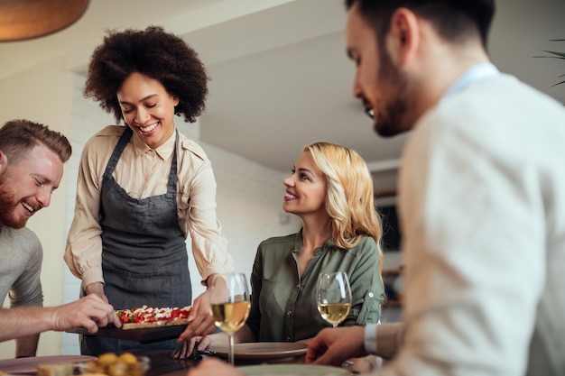 Souriante jeune femme servant le dîner à la maison.