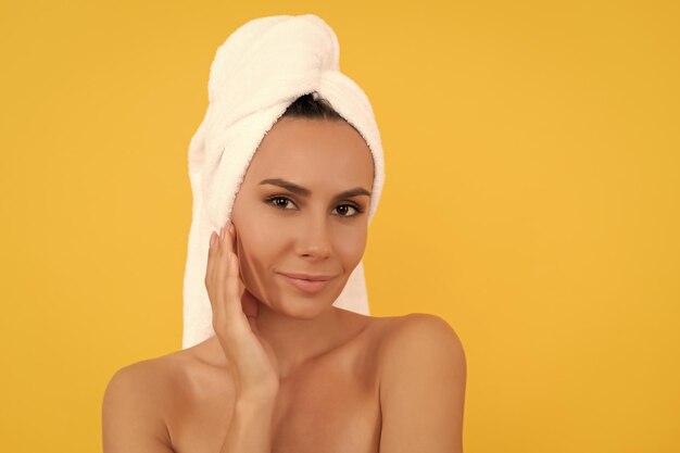 Souriante jeune femme avec une serviette après la douche sur fond jaune