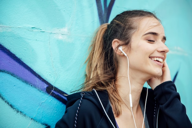 Souriante jeune femme avec smartphone et casque d&#39;écoute de la musique