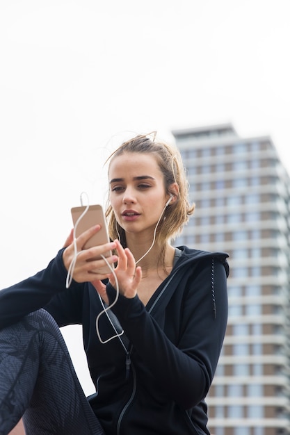 Souriante jeune femme avec smartphone et casque d&#39;écoute de la musique