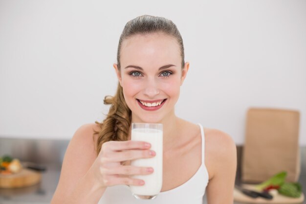 Souriante jeune femme tenant un verre de lait