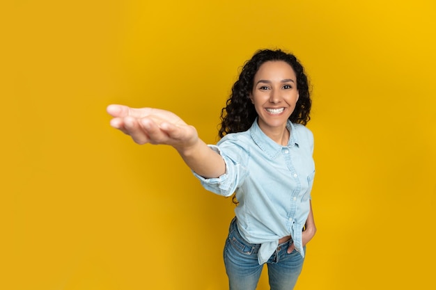 Souriante jeune femme tendant la main essayant de tenir quelque chose