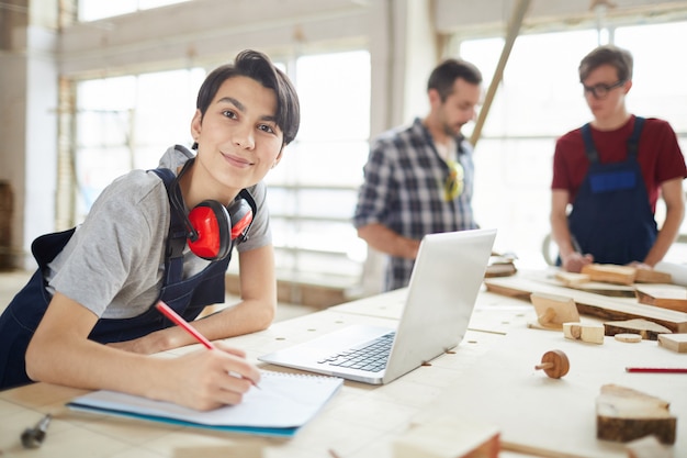 Photo souriante jeune femme travaillant dans l'atelier de charpentiers