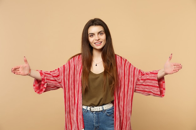 Souriante jeune femme en vêtements décontractés faisant des gestes démontrant la taille avec un espace de travail horizontal isolé sur fond de mur beige pastel. Les gens émotions sincères, concept de style de vie. Maquette de l'espace de copie.