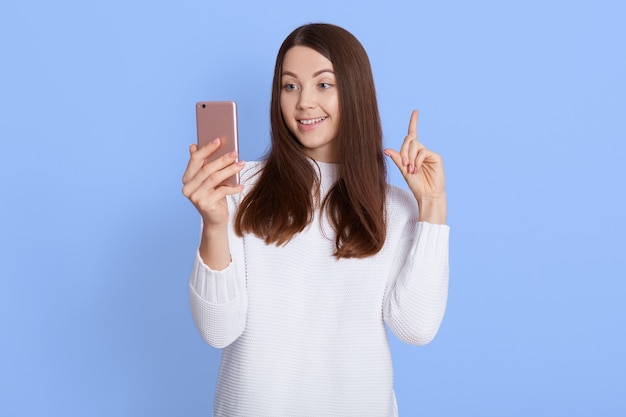 Souriante jeune fille aux cheveux noirs femme en pull blanc posant