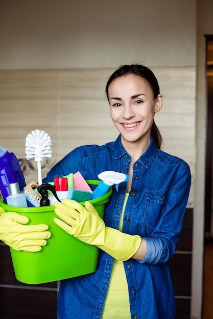 Souriante jeune fille avec l'équipement de nettoyage